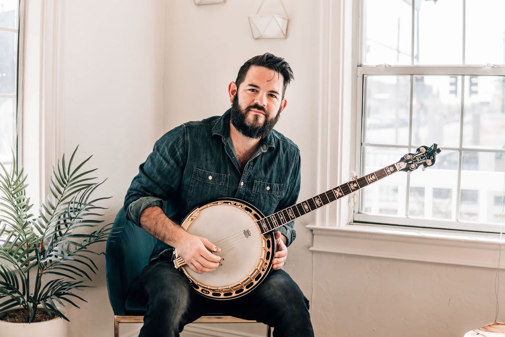 Jon Jimmerson holding a banjo in a bright music room